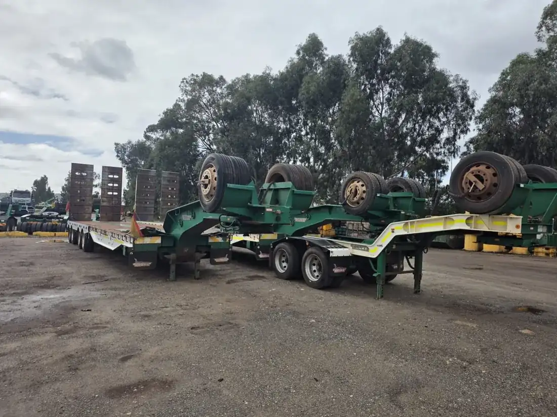 Green low-loader float trailers with stacked axle dollies parked in an Australian transport yard, ready for heavy-haulage work