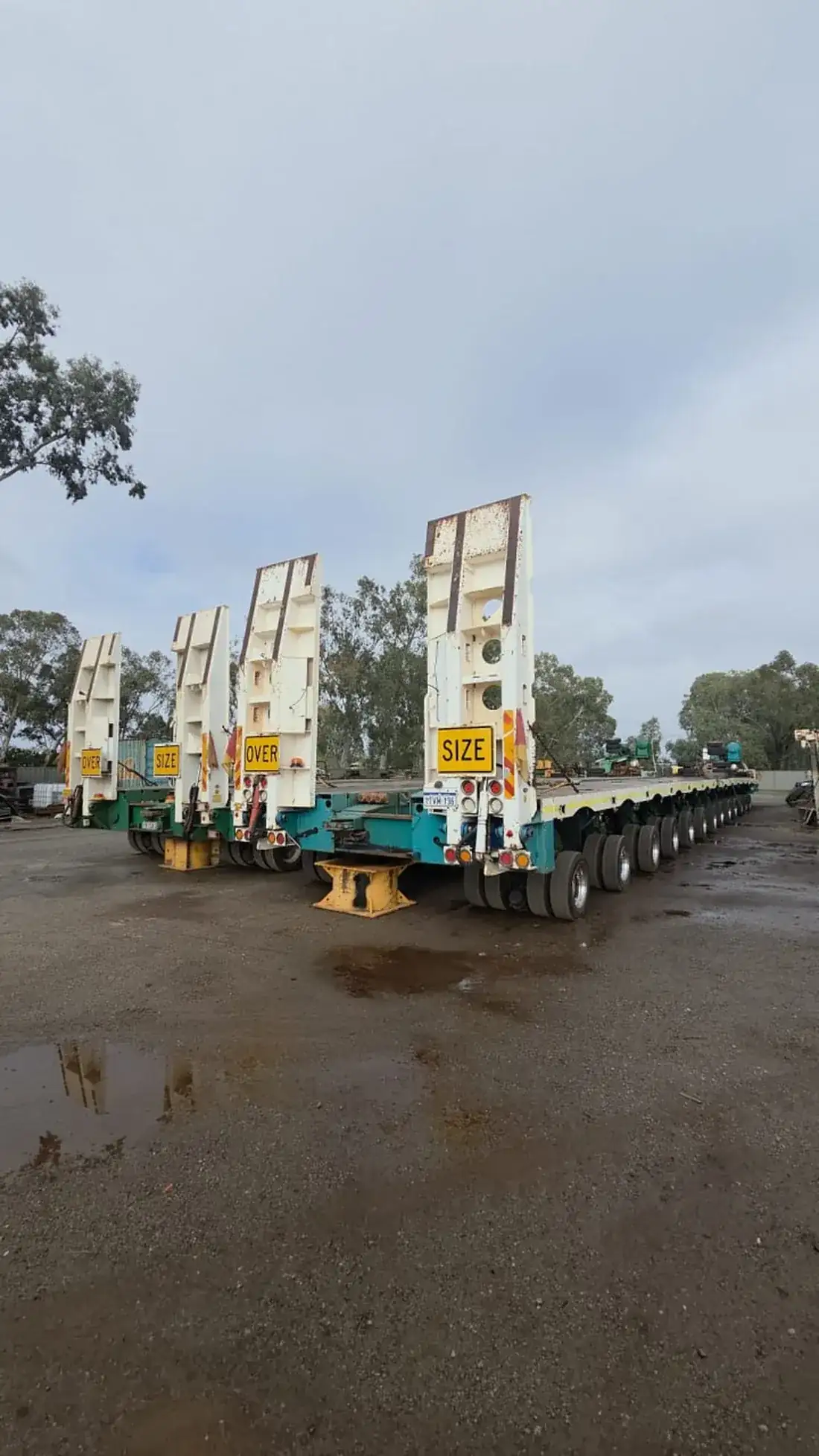 Multi-axle oversize float and low-loader trailers parked detached in an Australian transport yard, ready to be coupled and swapped between prime movers