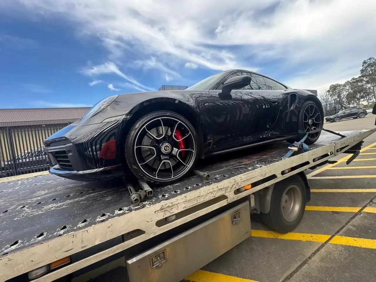 Tilt-tray tow truck carrying a car on a flatbed at an Australian yard