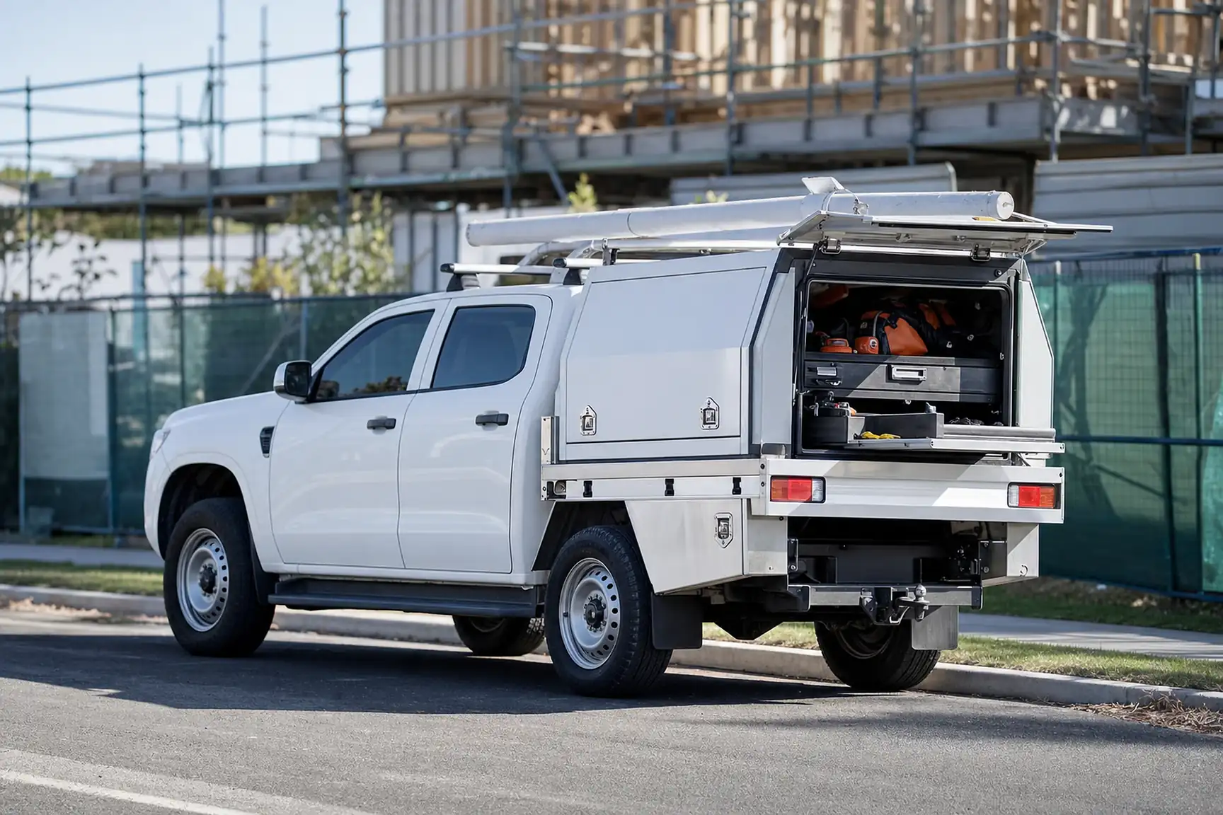 Australian tradesperson's dual cab work ute with canopy and toolboxes parked at a job site