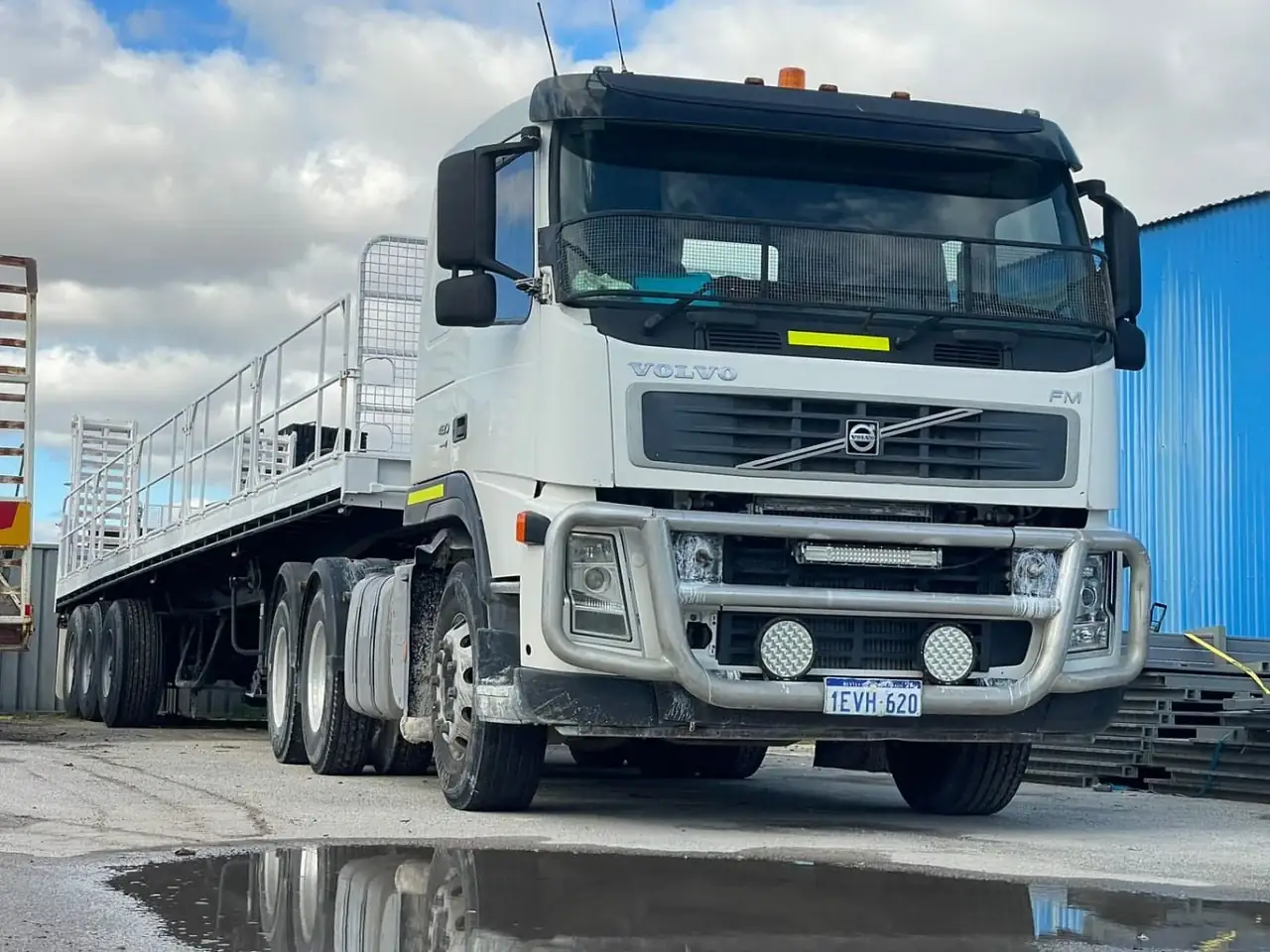 White Volvo FM prime mover with a flat top trailer at an Australian transport yard