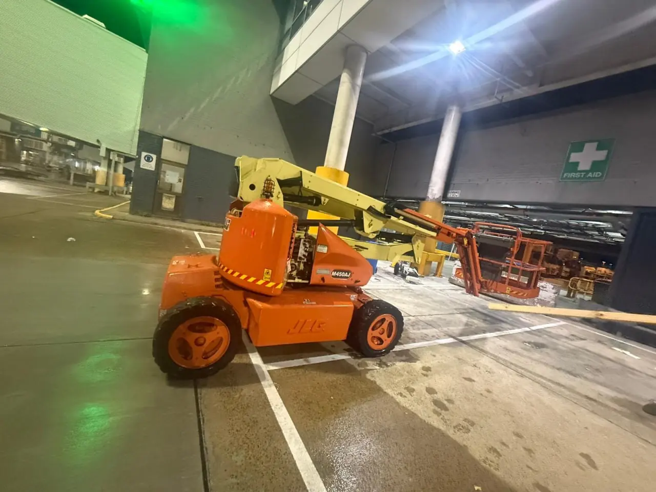 Orange articulating boom lift parked under cover at an Australian site