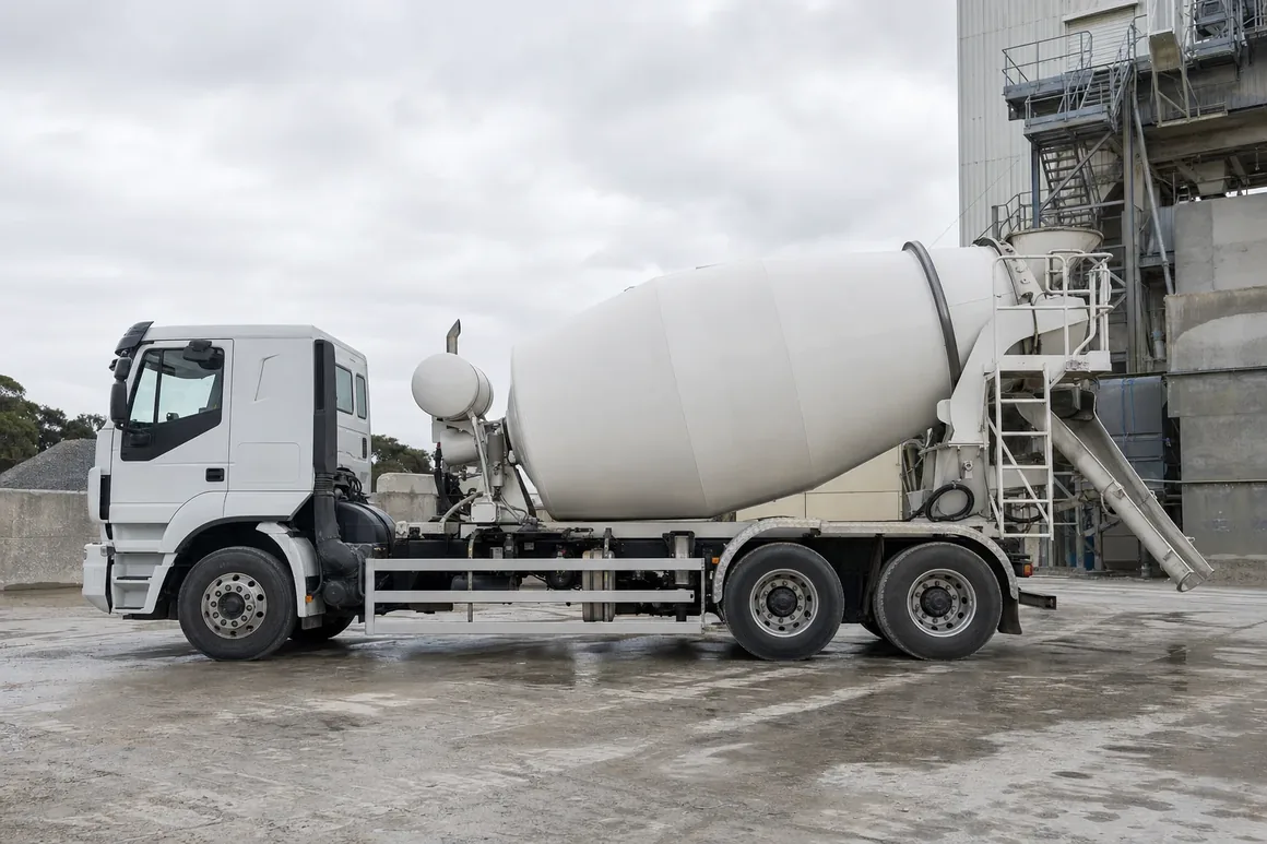 Concrete agitator truck parked side-on at an Australian batching plant, mixer drum and rear chute in view