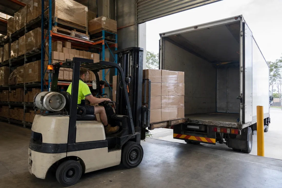 Forklift loading a pallet of cartons into a pantech truck at an Australian warehouse loading dock