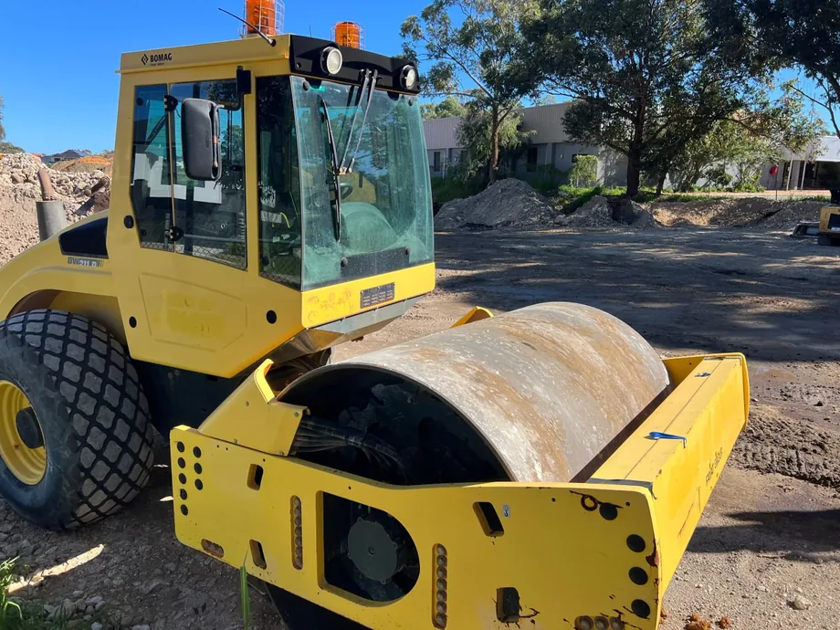 Yellow single drum vibratory roller parked on a compacted work pad