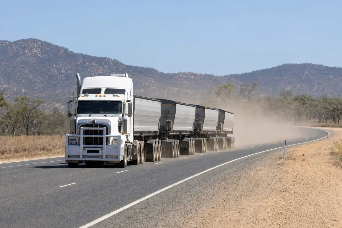 Road train with side tipper trailers on a sealed haul road through dry inland Queensland ranges