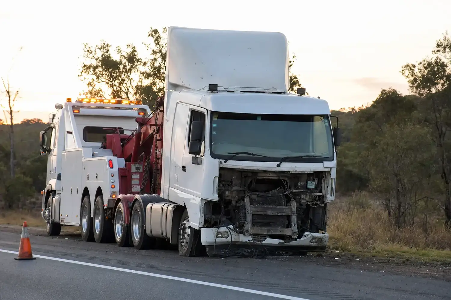 Heavy tow truck recovering a damaged prime mover on the shoulder of an Australian highway